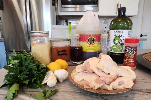 Ingredients for Cajun Chicken marinade arranged on a kitchen counter, including garlic, lemons, parsley, smoked paprika, soy sauce, Worcestershire sauce, oil, and red pepper.