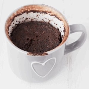 Chocolate mug cake freshly baked in a gray mug with a white heart, ready to eat.