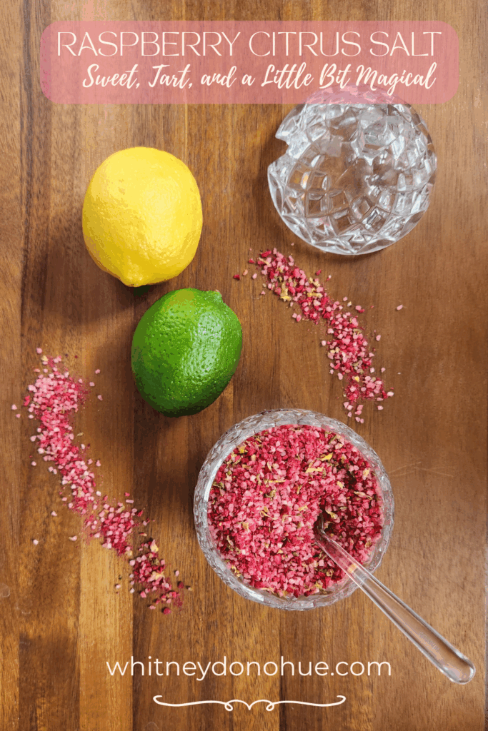 Pinterest graphic showing a lemon, lime, and a glass jar of vibrant citrus salt on a wooden board, with the text "Raspberry Citrus Salt - Sweet, Tart, and a Little Bit Magical" overlaid