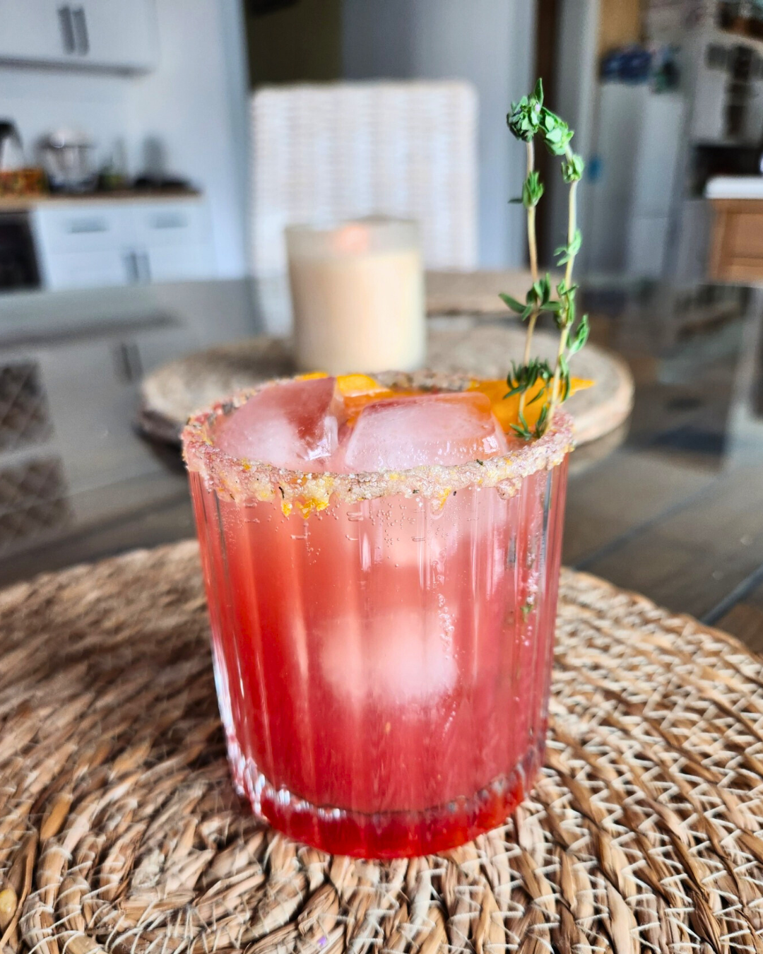 Twilight Orchard citrus cranberry mocktail with rosemary citrus salt rim and thyme sprig