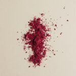Loose hibiscus powder scattered on a light beige surface